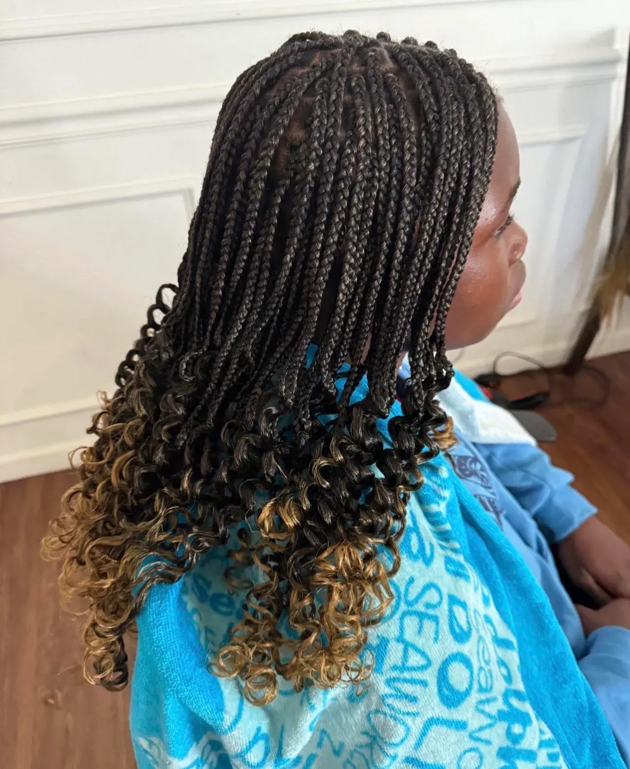 Children's knotless box braids finished with honey-blonde curly ends, side view